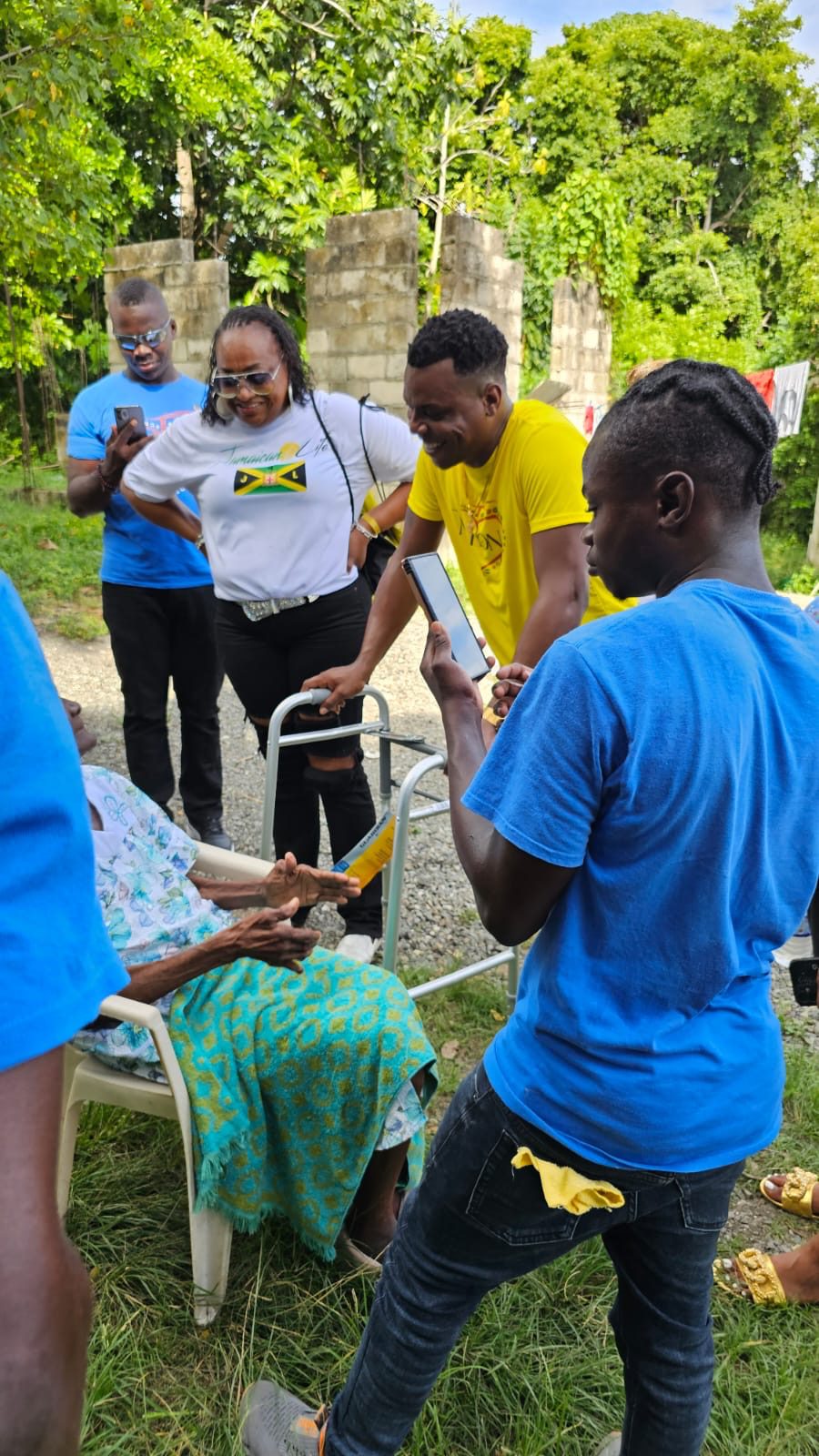 Group interacting with elderly person outdoors.