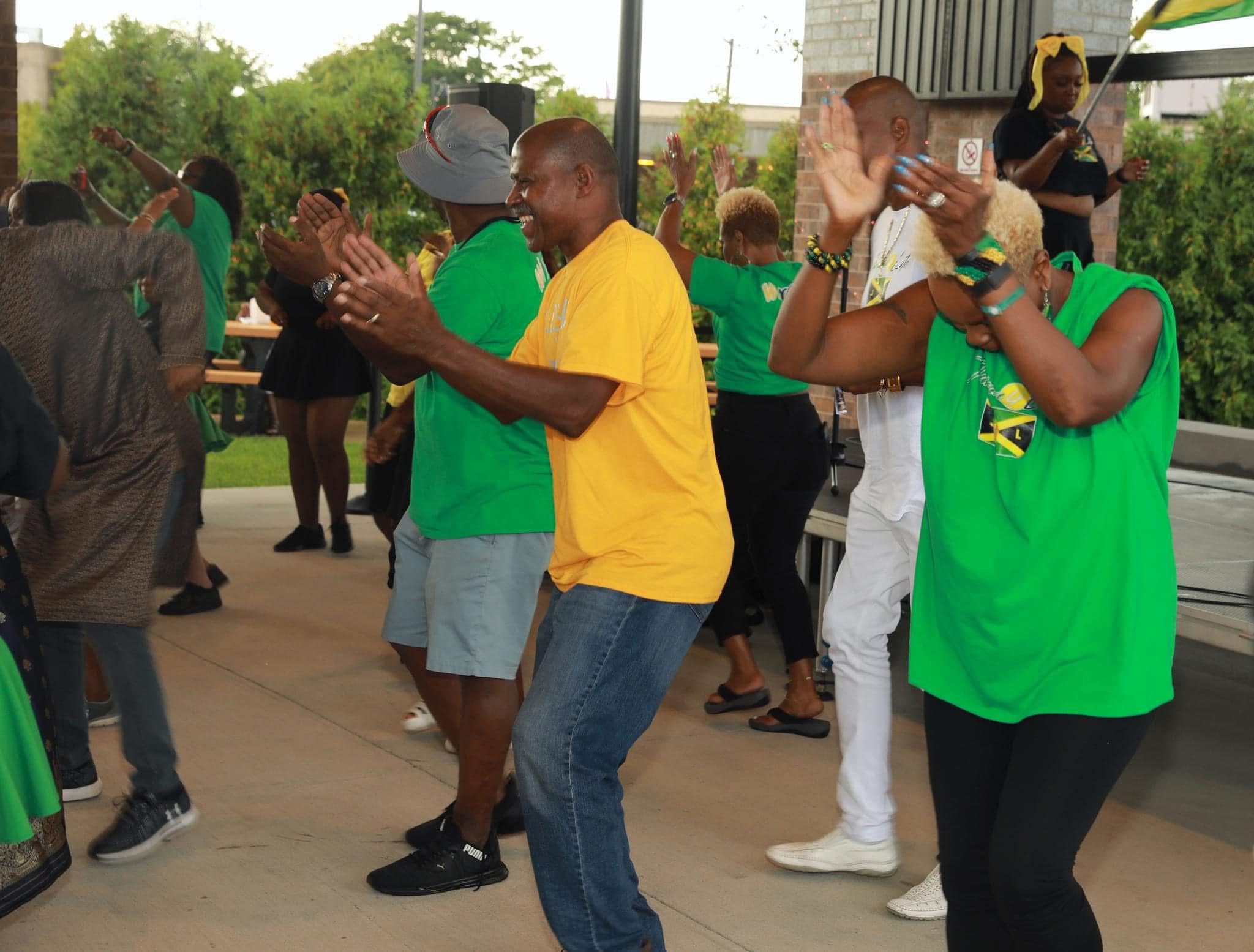 People dancing in colorful shirts outdoors.
