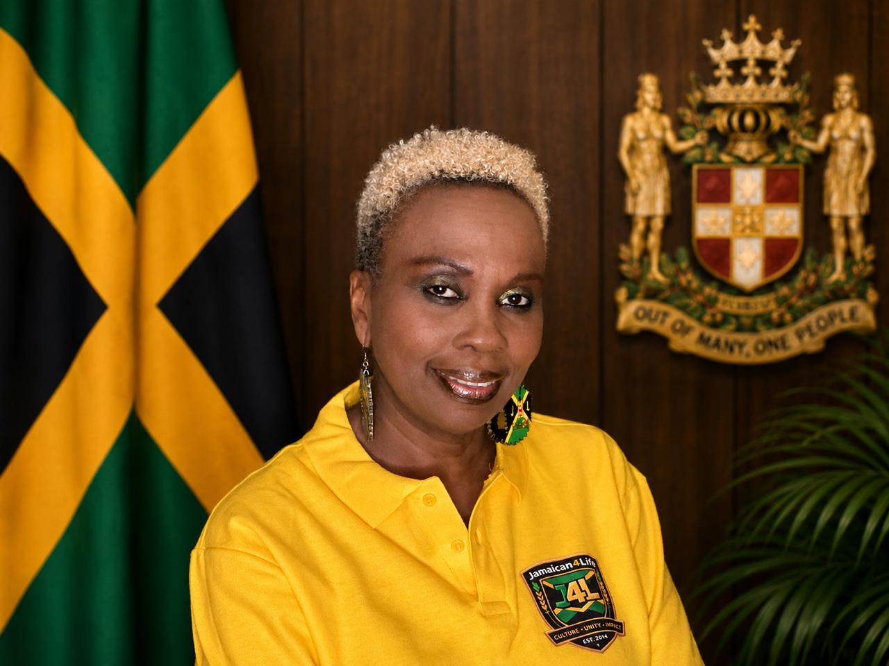 Woman in yellow shirt, Jamaican flag background.