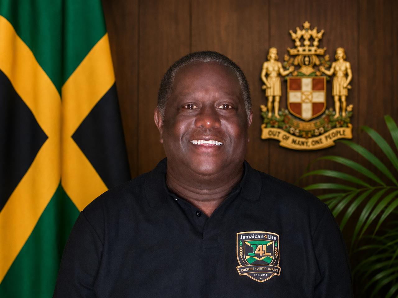 Smiling man in front of Jamaican flag.
