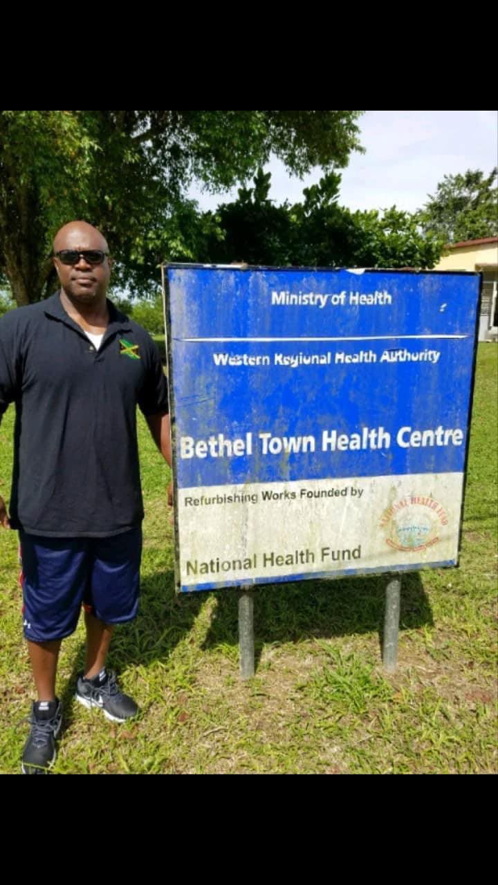 Man beside Bethel Town Health Centre sign