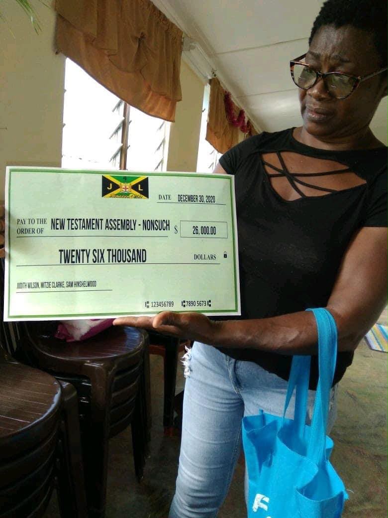 Woman holding large ceremonial check twenty-six thousand