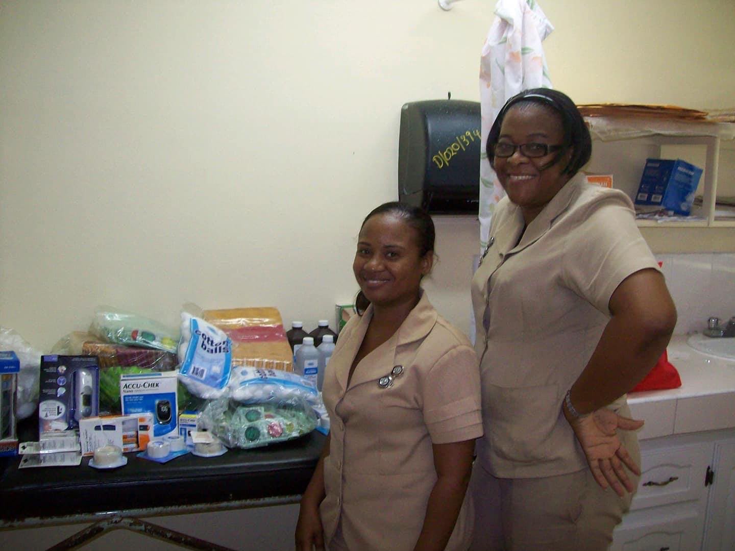 Two clinic nurses smiling beside medical supplies