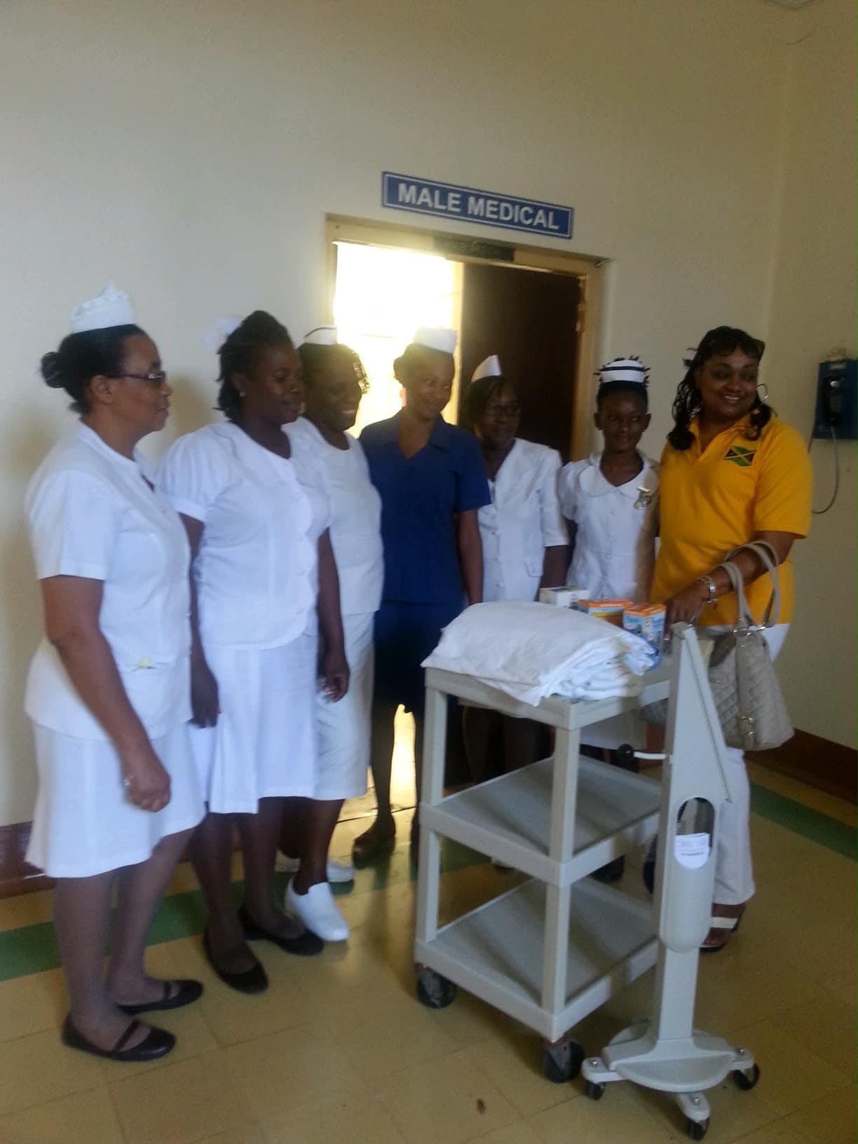Nurses posing with medical cart under sign