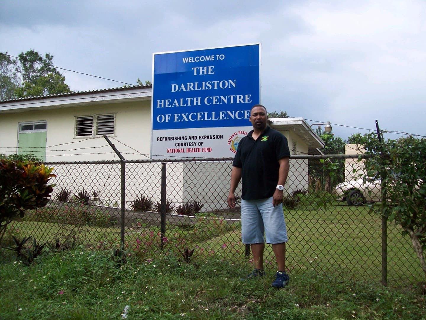 Person standing by Darliston Health Centre sign