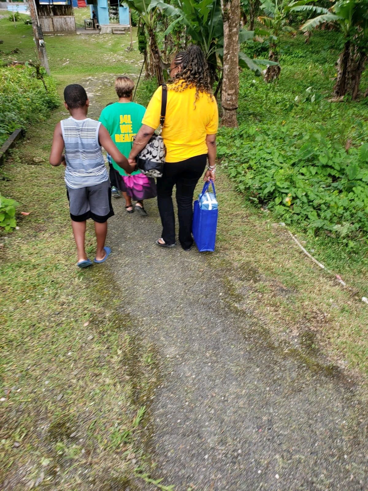 Woman walking with two children carrying bags